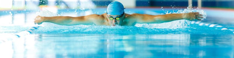 Photo of sporty man sailing down path in pool in training on blurred background