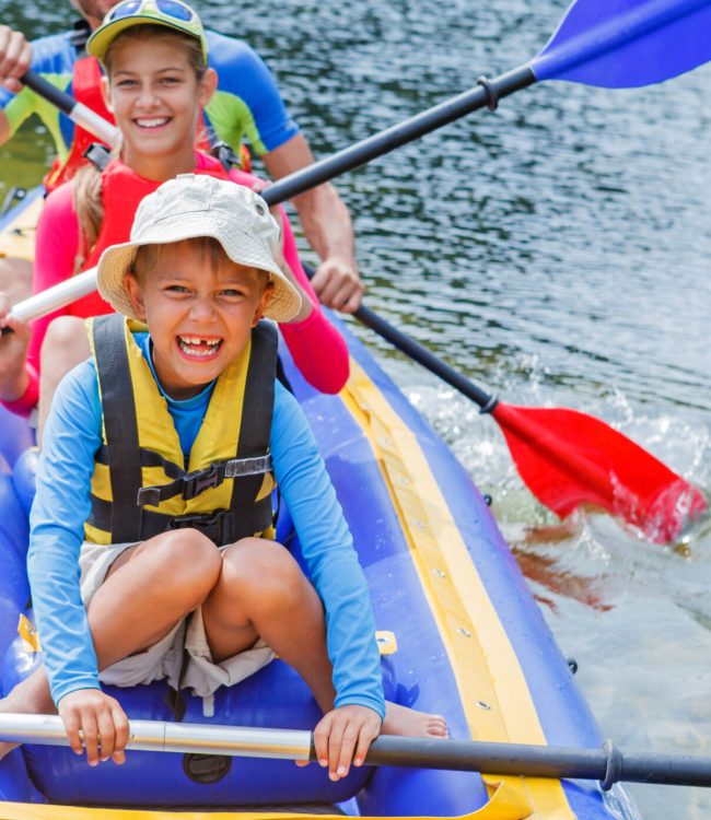 Active happy family. Boy with his sister and father having fun together enjoying adventurous experience kayaking on the river on a sunny day during summer vacation