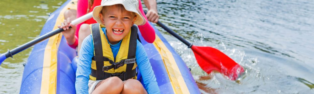 Active happy family. Boy with his sister and father having fun together enjoying adventurous experience kayaking on the river on a sunny day during summer vacation