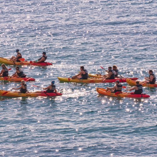 NAPLE, ITALY - Sep 25, 2021: Happy young caucasian group of friends kayaking on sea with sunset in the backgrounds. Having fun in leisure activity.