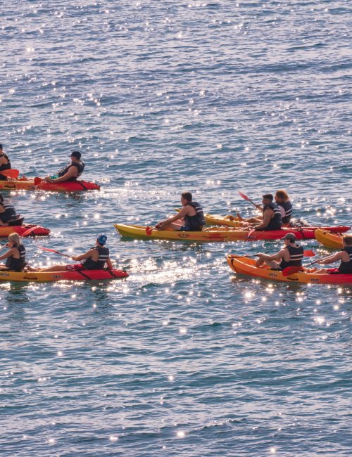 NAPLE, ITALY - Sep 25, 2021: Happy young caucasian group of friends kayaking on sea with sunset in the backgrounds. Having fun in leisure activity.