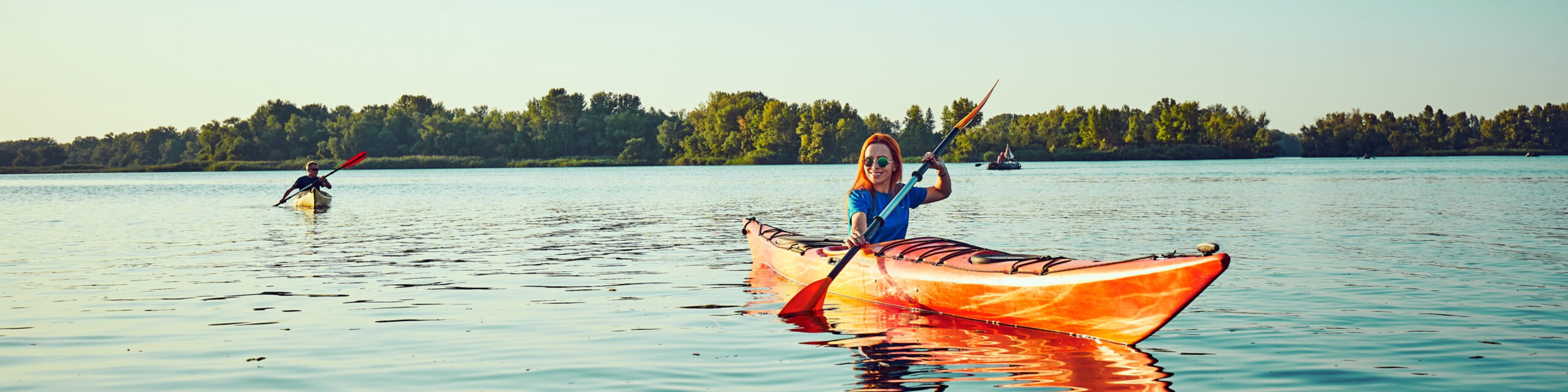 Kayaking couple ride along the river at sunset